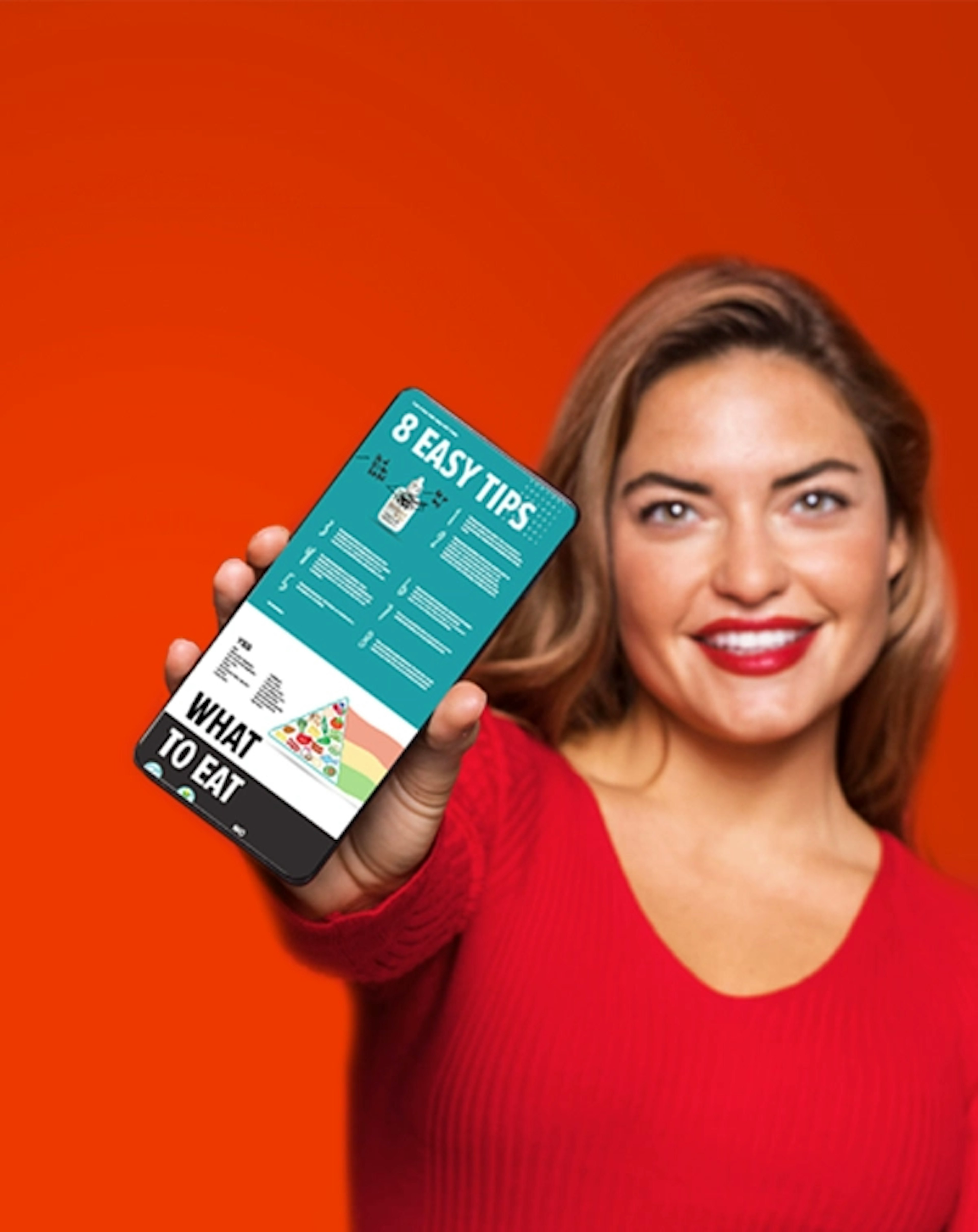 A blonde woman in a red shirt smiling and holding up a phone showing the digital keto start guide