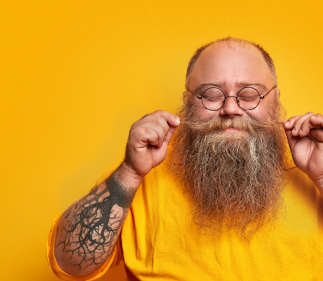 a man smiling and playing with his moustache