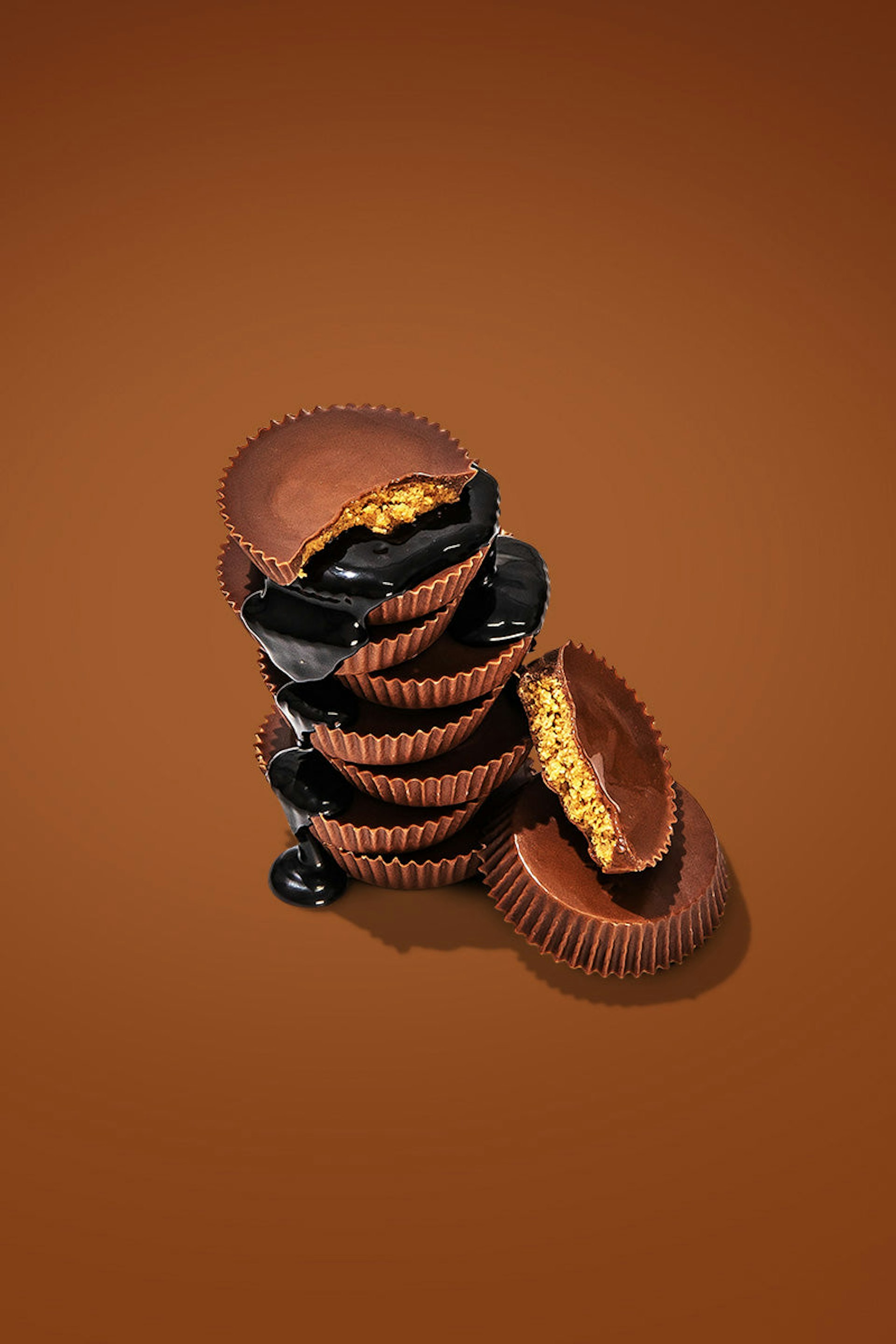 A pile of chocolate peanut butter cups, with some drizzles of chocolate syrup