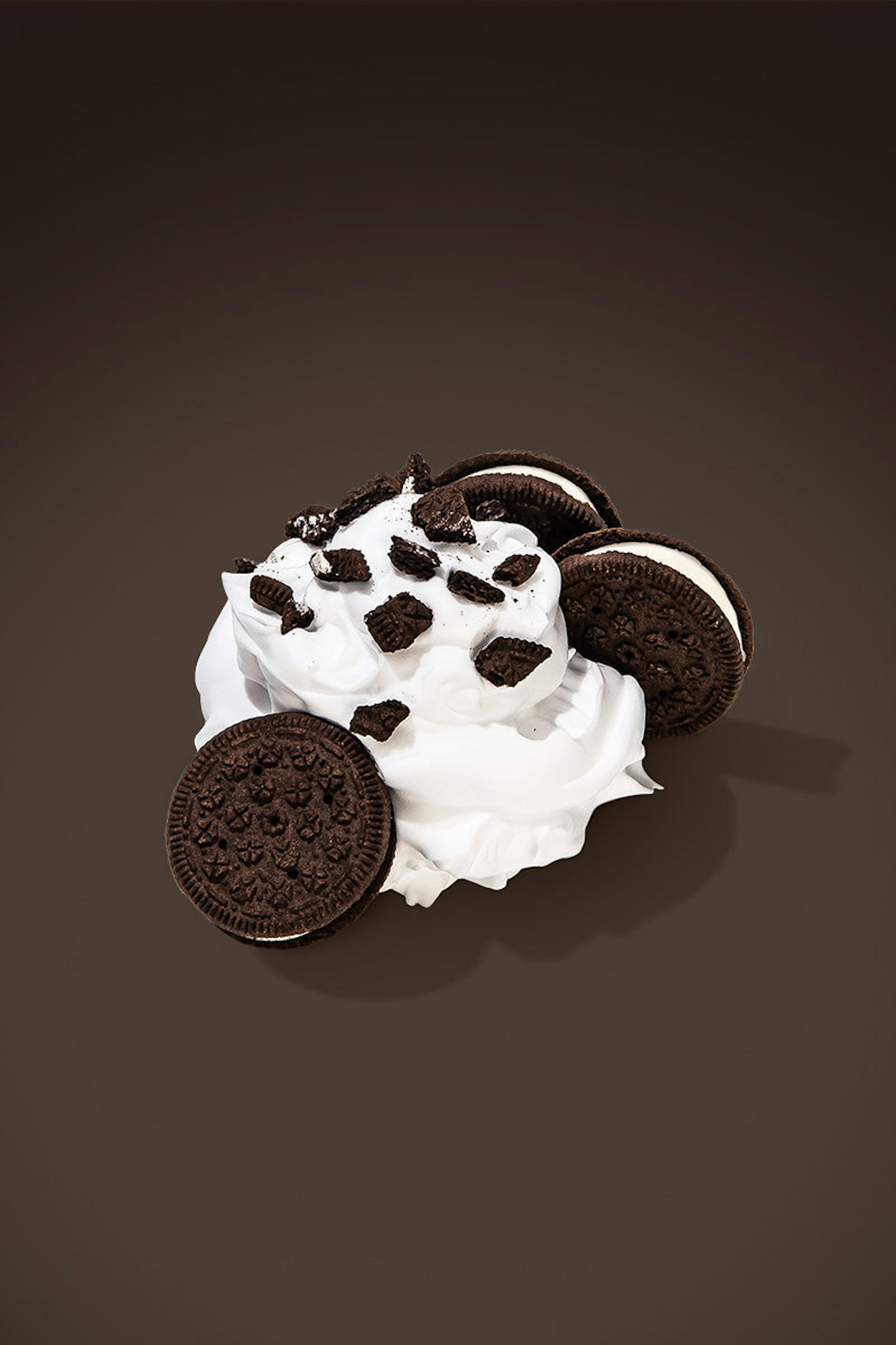 Oreo cookies next to a dollop of whipped cream with cookie crumbs on top