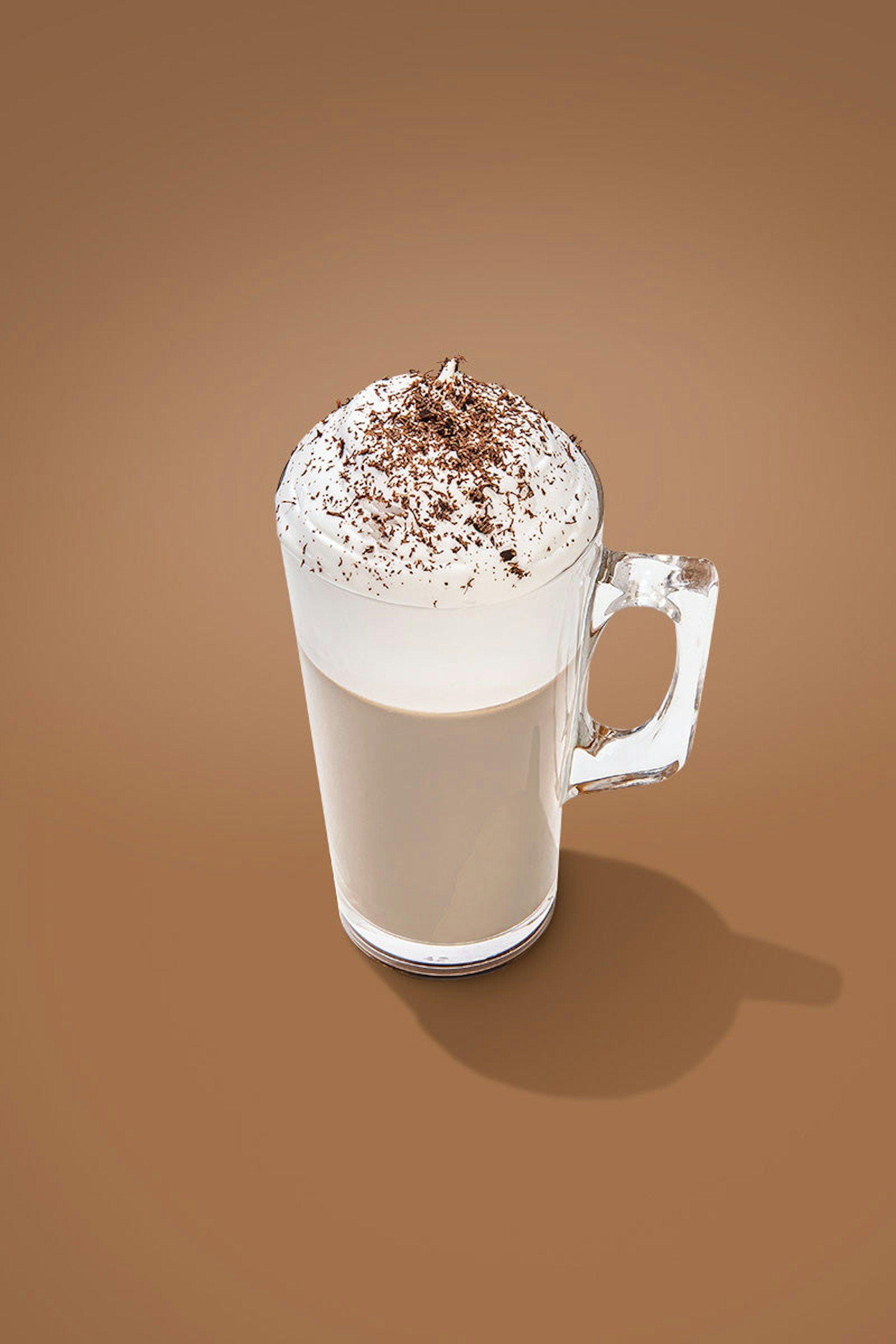 A clear, old-fashioned glass full of Irish cream liqueur and topped with whipped cream