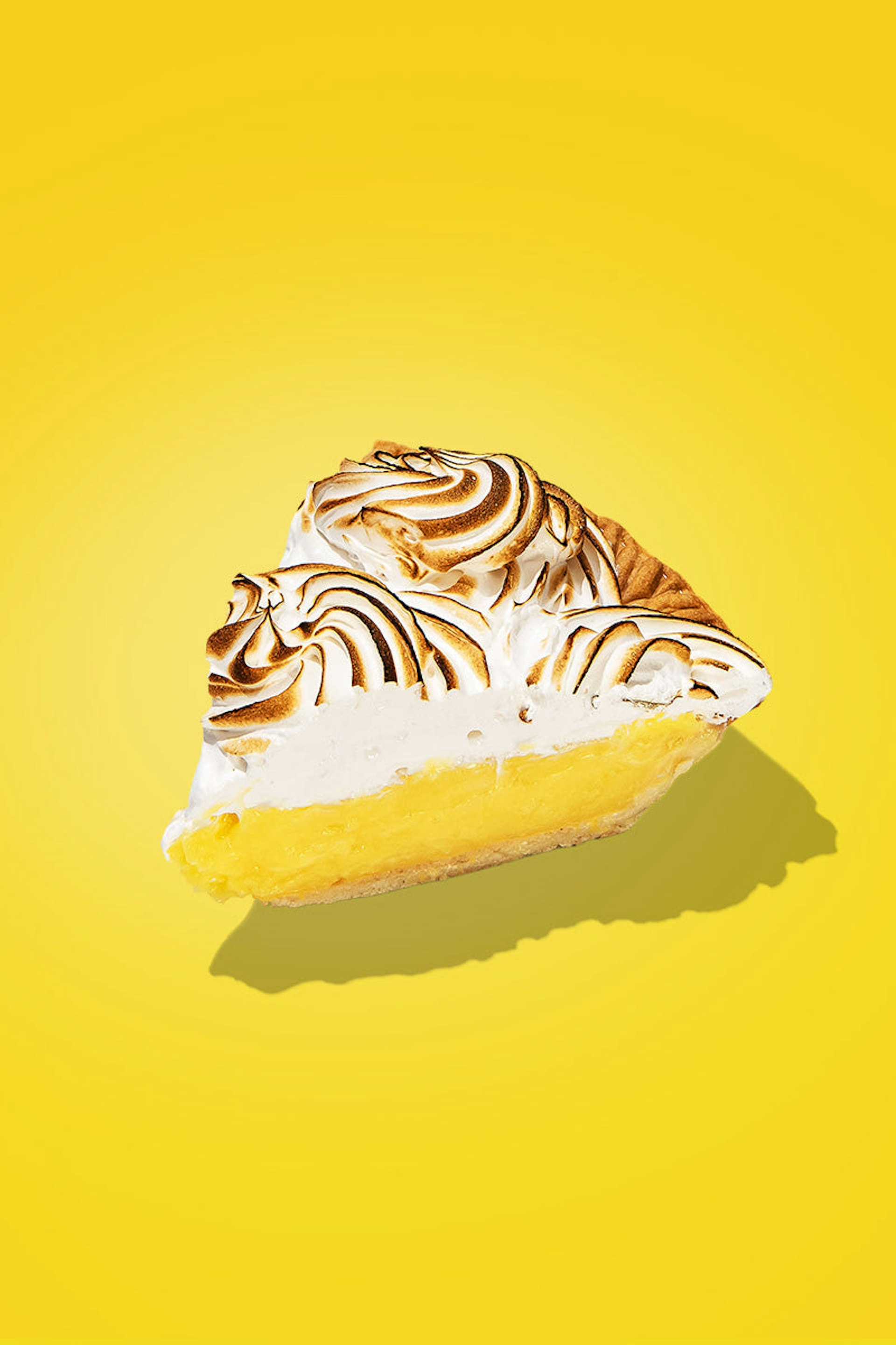 A slice of lemon meringue pie, with the meringue on top toasted to perfection