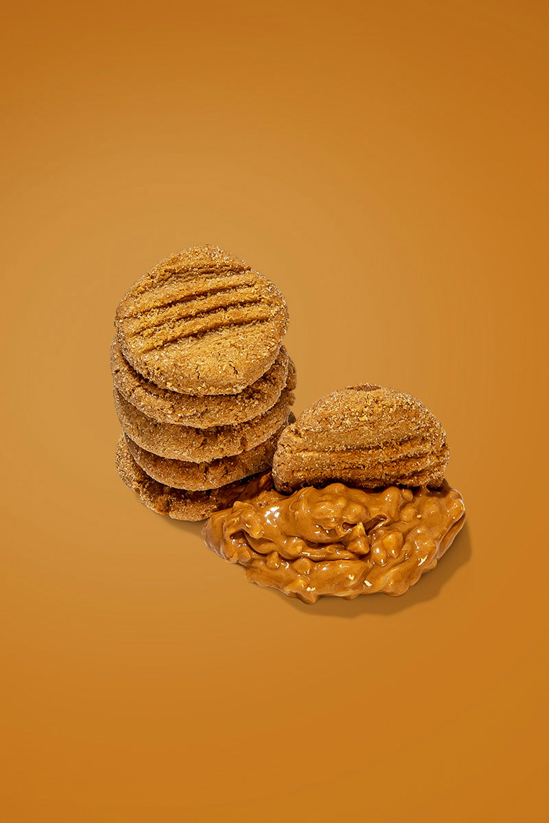 A small stack of peanut butter cookies with a dollop of peanut butter on the side