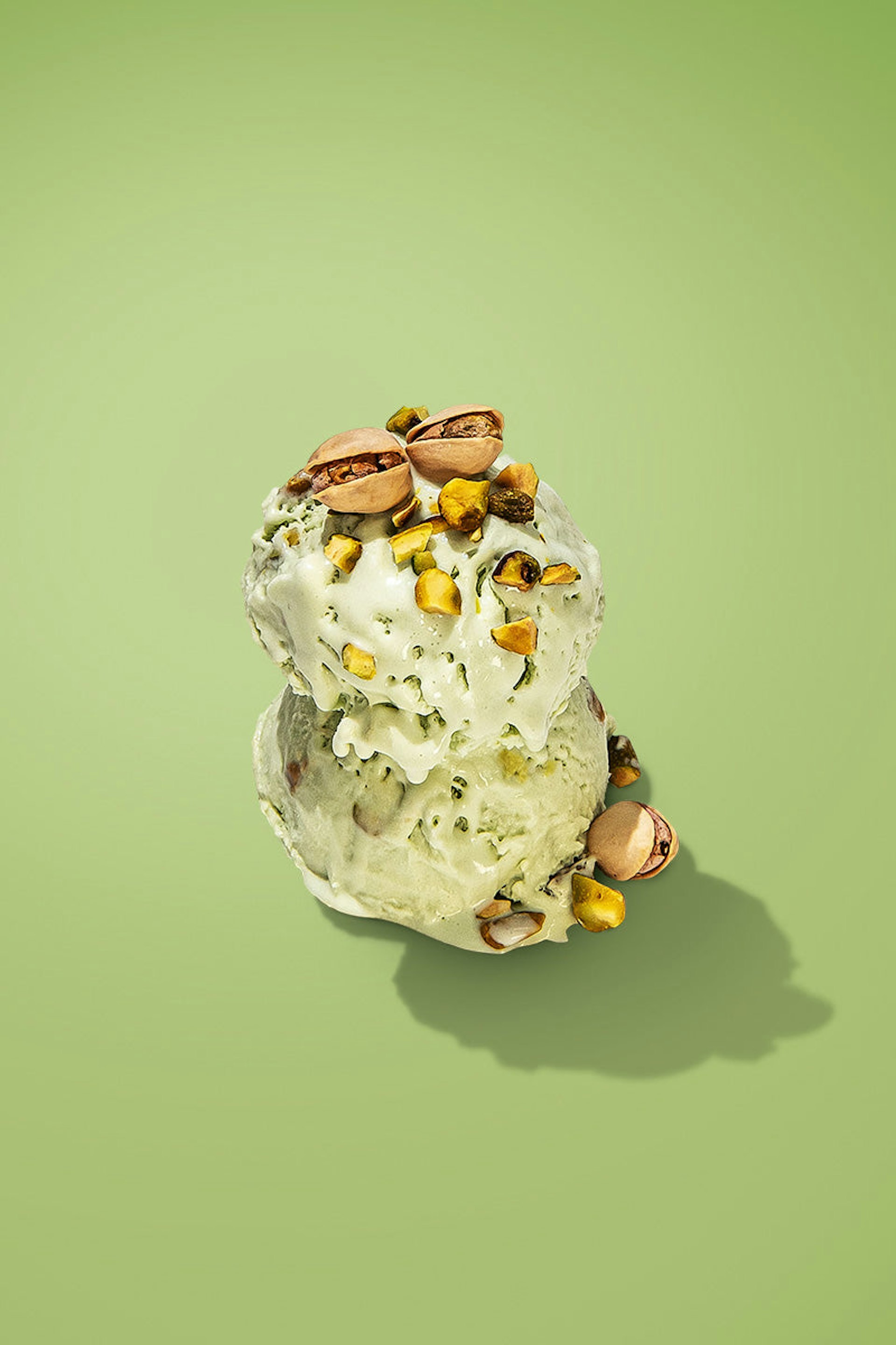 Two scoops of pistachio ice cream, garnished with chopped and whole pistachios