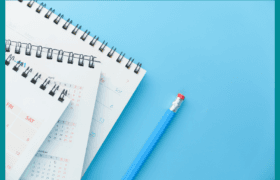 Three desk calendars with black spiral binding and white pages, displaying April and December dates, lie on a light blue background next to a blue pencil with a red eraser.