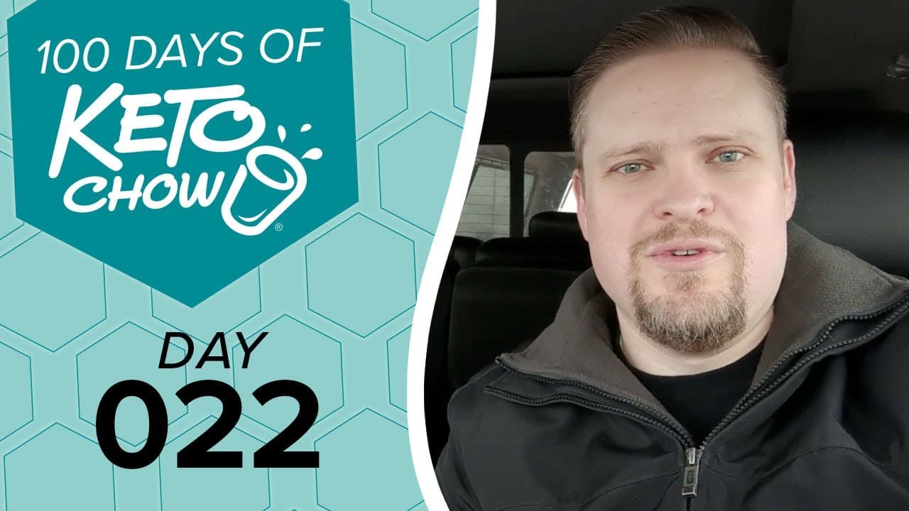 Image displaying a man on the right and a graphic on the left. The graphic, in teal and light blue, features the text 100 DAYS OF KETO CHOW and DAY 022. The Keto Chow brand logo includes a white shaker cup icon.