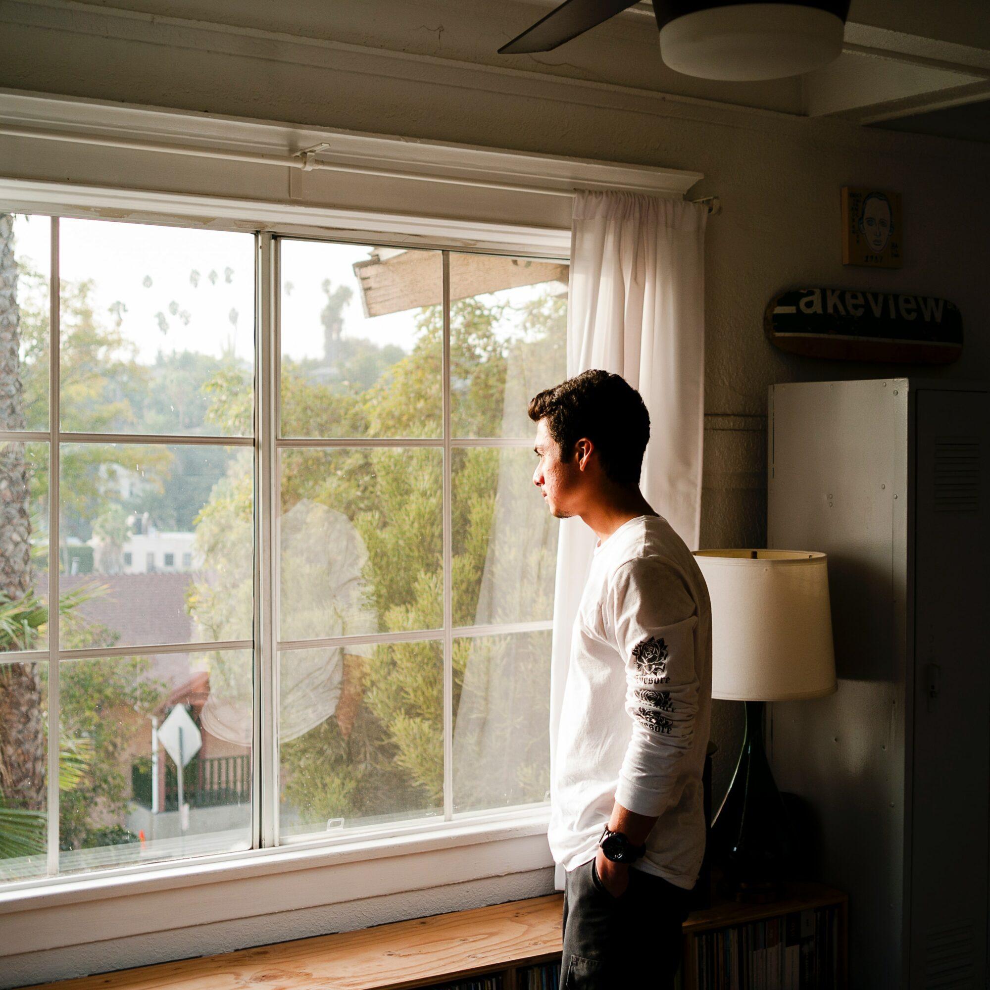 man looking out window