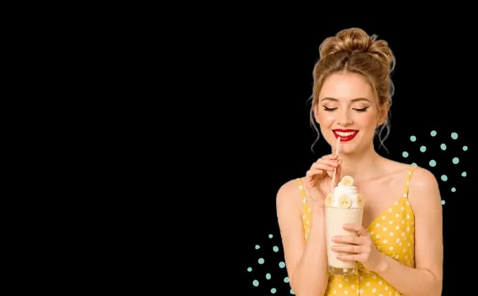 A smiling woman drinking a Banana Keto Chow shake.