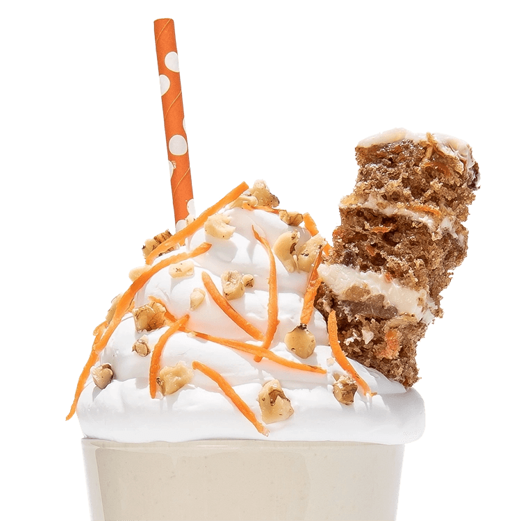 A carrot cake keto chow shake garnished with carrot slices and a slice of carrot cake with an orange polka dot straw