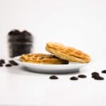 Side view - Two Chocolate Chip Chaffles on a white plate surrounded by chocolate chips.