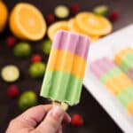 Close up of a green, orange and pink striped popsicle.