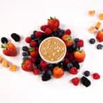 Close up - bowl of Salted Caramel sauce surrounded by mixed berries.