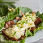 Close up of egg salad on top of bacon slices, lying on a lettuce leaf