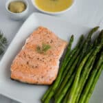 Asparagus spears and salmon on white plate. Side dish of dipping sauce.