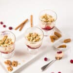 Top view - Three parfait goblets on a white tray, layered with cranberry sauce and pumpkin spiced yogurt.