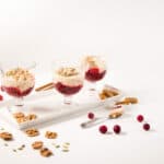 Three parfait goblets on a white tray, layered with cranberry sauce and pumpkin spiced yogurt.