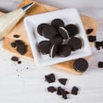 White plate filled with Dark Chocolate Cookie Crumbs. Cookies and and icing bag on the side.
