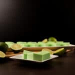Close up - White tray with squares of Creamy Key Lime Jellies. Cut limes to the side.
