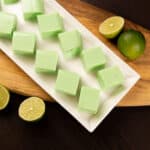 White tray with squares of Creamy Key Lime Jellies. Cut limes to the side.