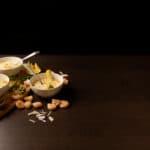 Three white bowls filled with Seafood Bisque. Lemon wedges and shrimp on the side.