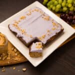 A white square plate with Peanut Butter Blondies and Grape Frosting.
