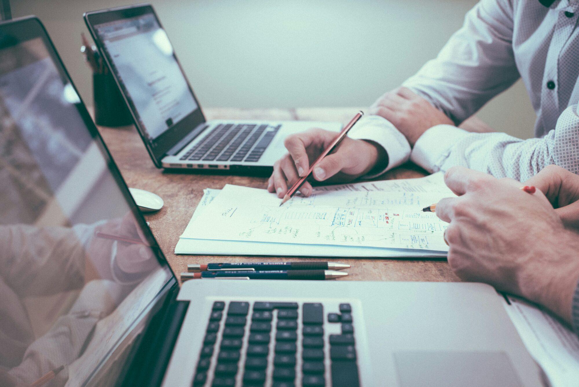 Closeup of desk with coworkers working on research together for keto research roundup article